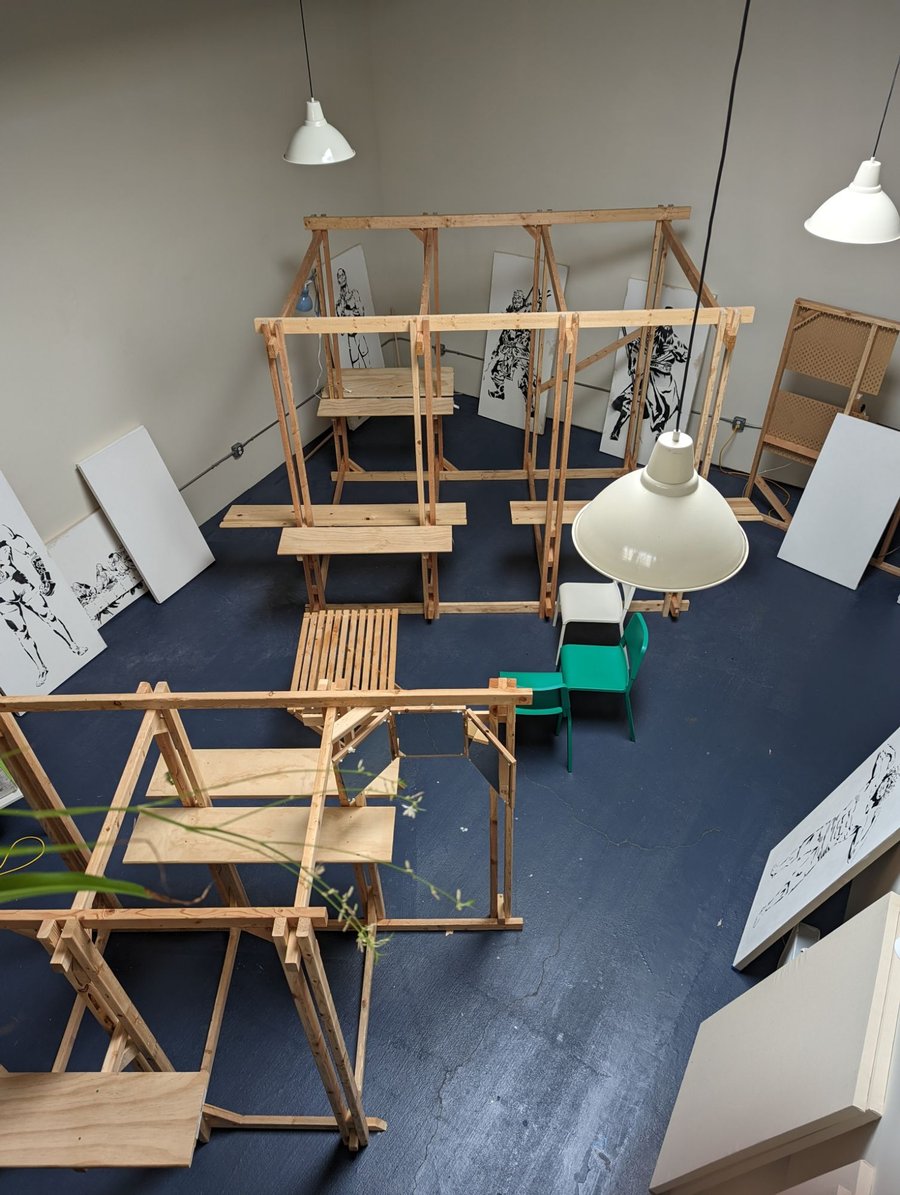Overhead view of a studio with hand-framed timber painting stations, benches, and stencil paintings on display
