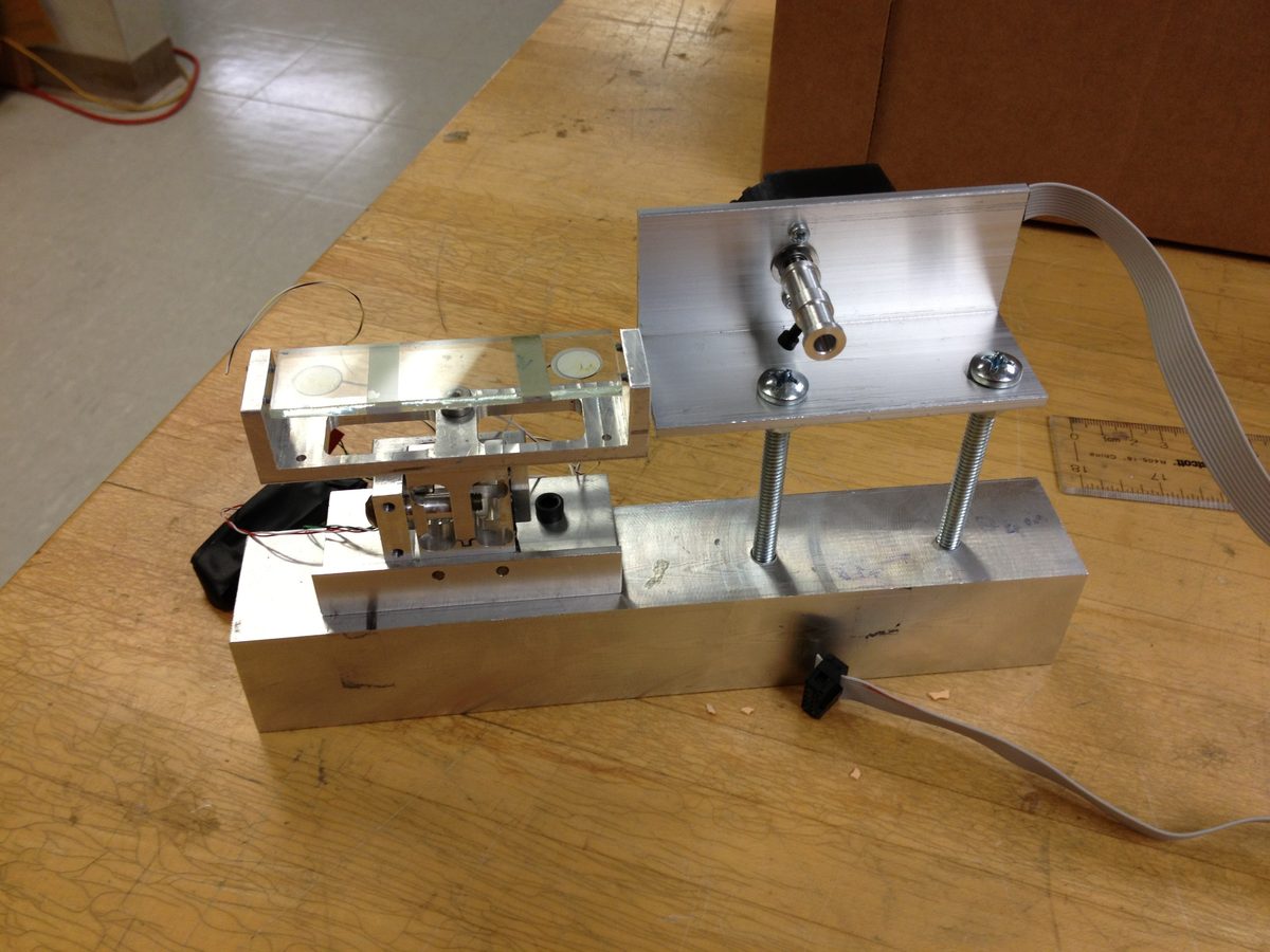 Machined aluminum finger-tracking mechanism with encoder on a workbench