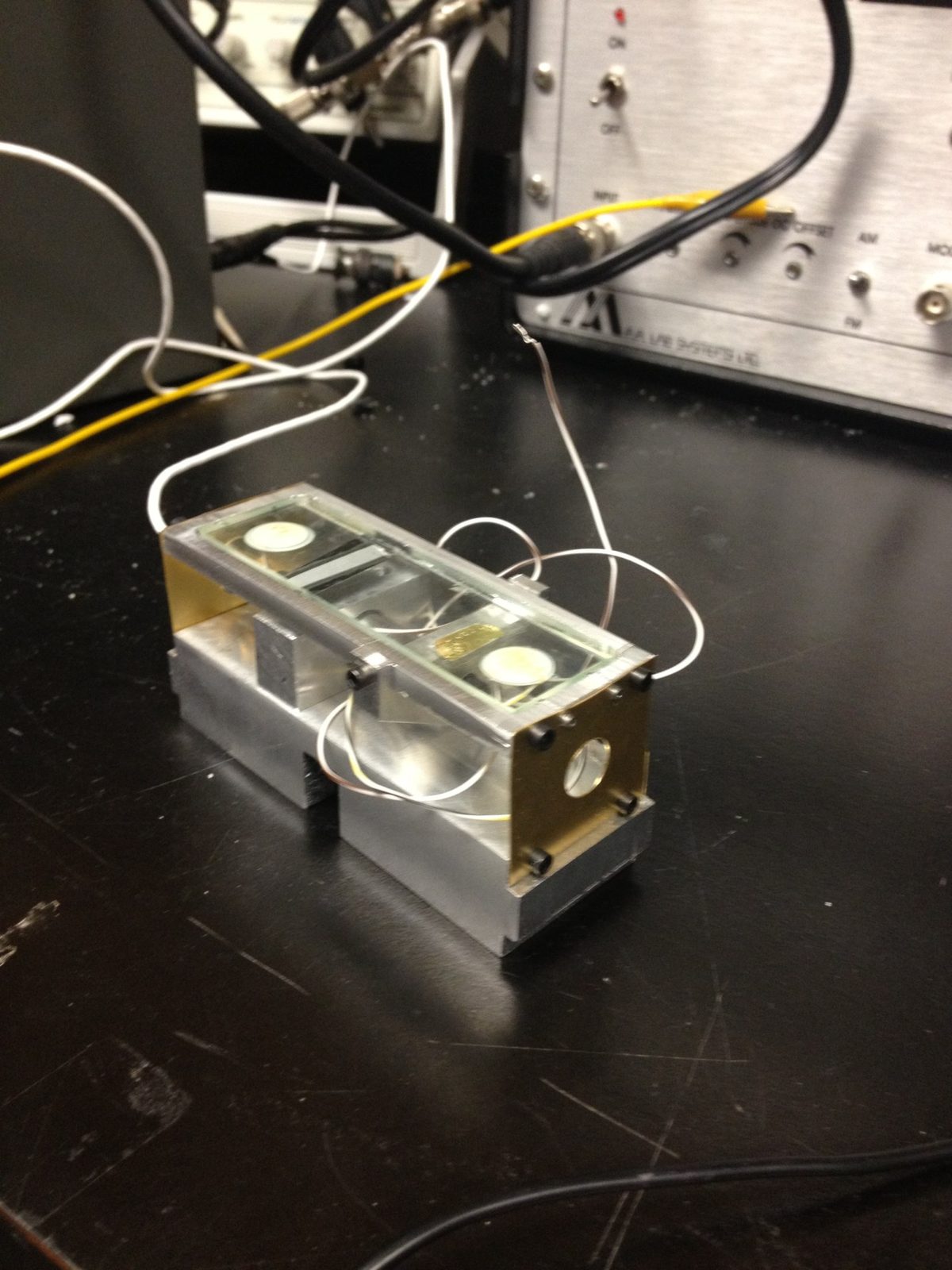Machined aluminum and brass force-sensor fixture holding a glass plate