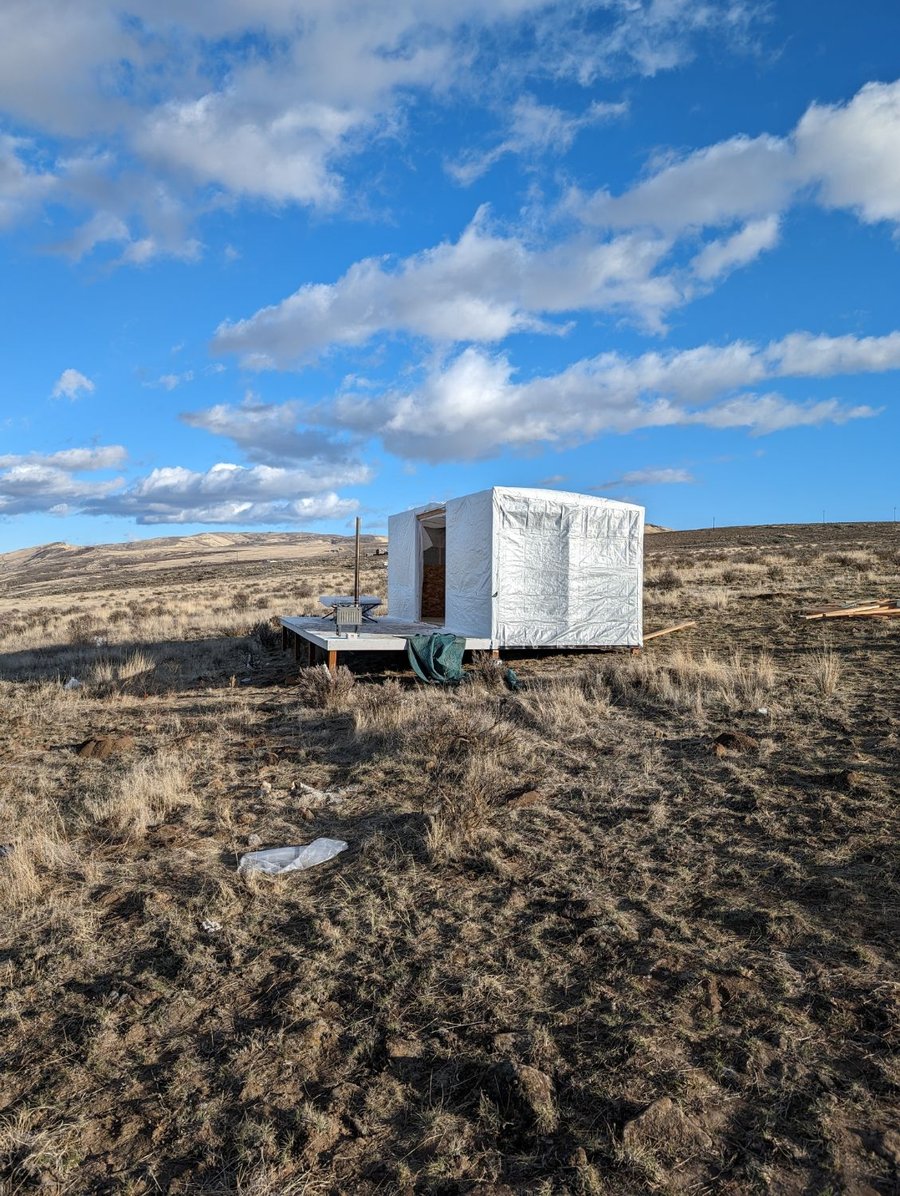 The wrapped homestead structure standing alone under a blue sky in Yakima